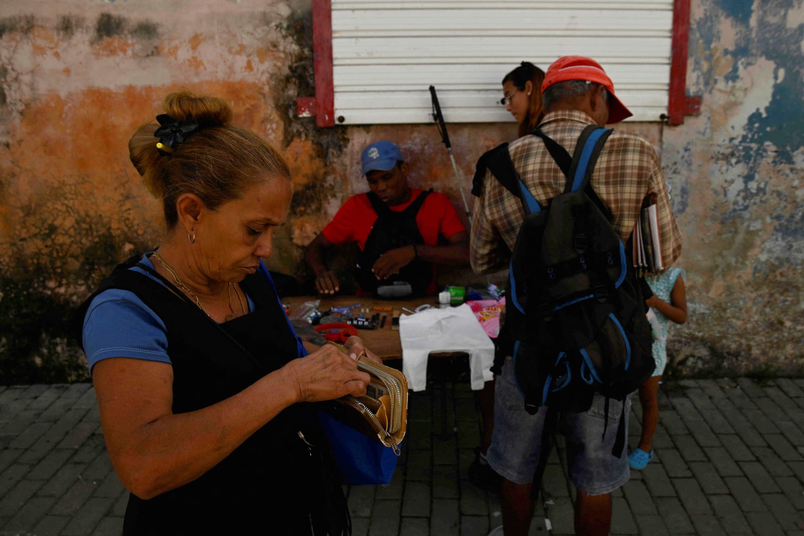 Una mujer cuenta dinero para comprar artículos a un vendedor ambulante en La Habana, mientras los cubanos de todos los ámbitos de la vida se preparan para sobrevivir ante los apagones aparentemente interminables y el aumento vertiginoso de los precios de los alimentos, el combustible y el transporte, mientras Estados Unidos amenaza con asfixiar a la nación comunista. Cuba, 26 de enero de 2026. REUTERS/Norlys Pérez