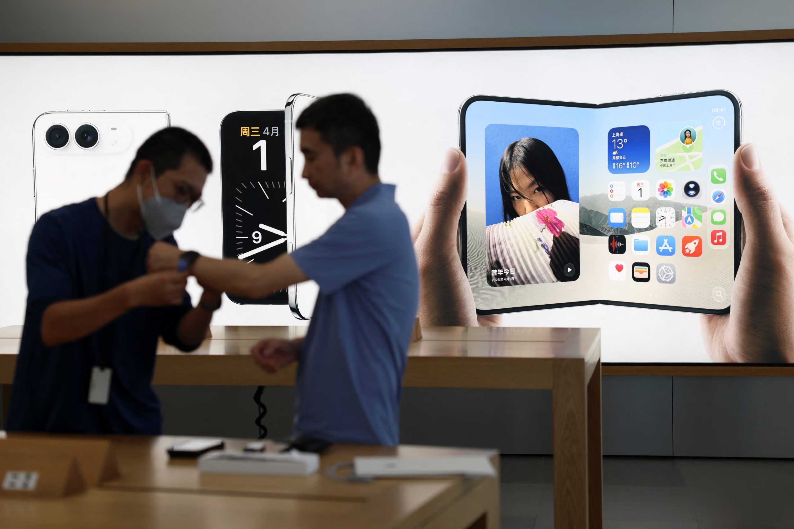 A staff member attends to a customer near an advertisement for Apple's foldable smartphone iPhone Duo, at an Apple Store in Beijing, China September 18, 2026. REUTERS/Tingshu Wang