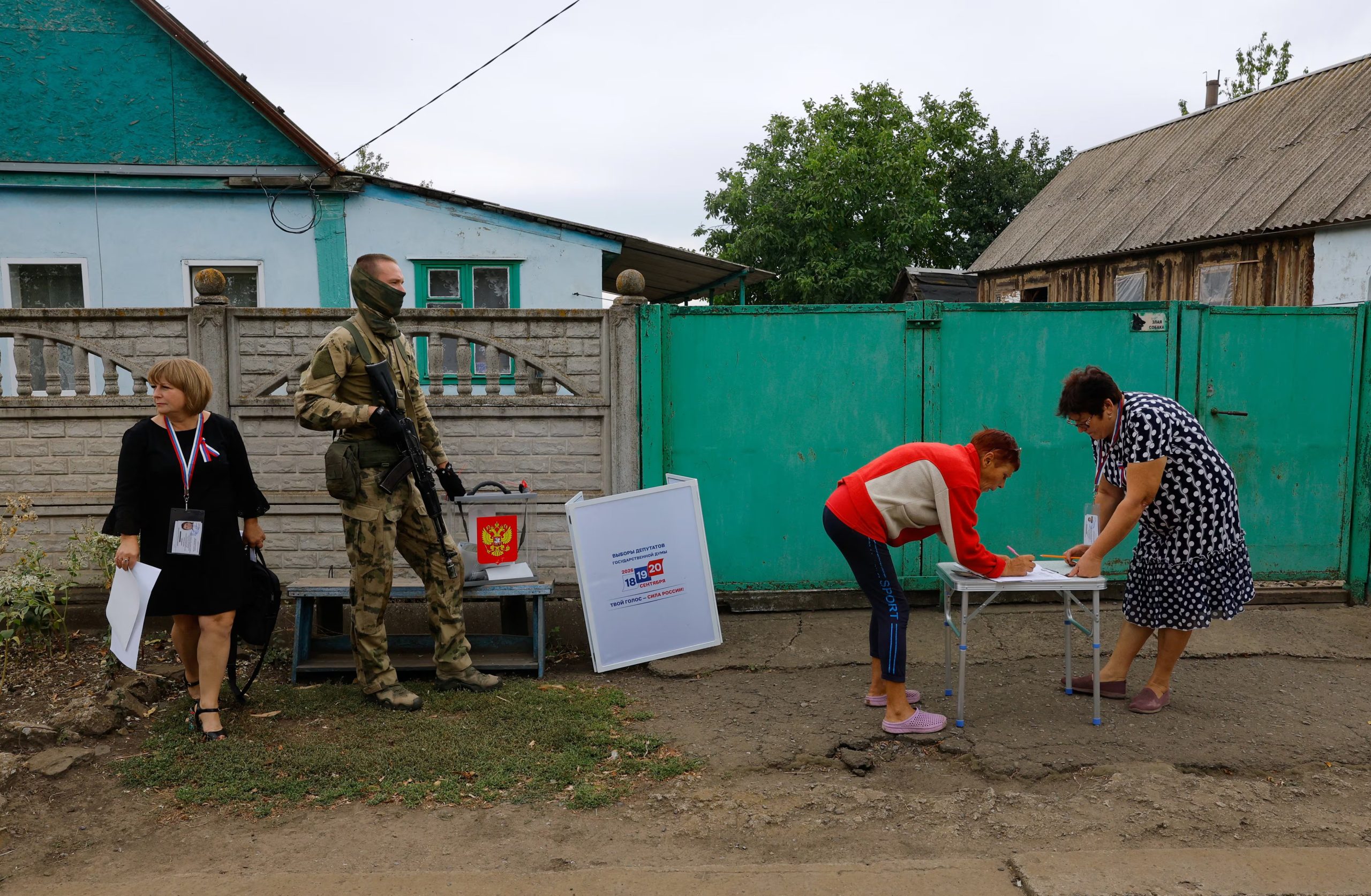 Un votante completa documentos durante el voto domiciliario en Verbovka, Donetsk, escoltado por un militar ruso. Es la primera vez que Rusia habilita mesas para su Parlamento en territorio ucraniano ocupado. (REUTERS/Alexander Ermochenko)