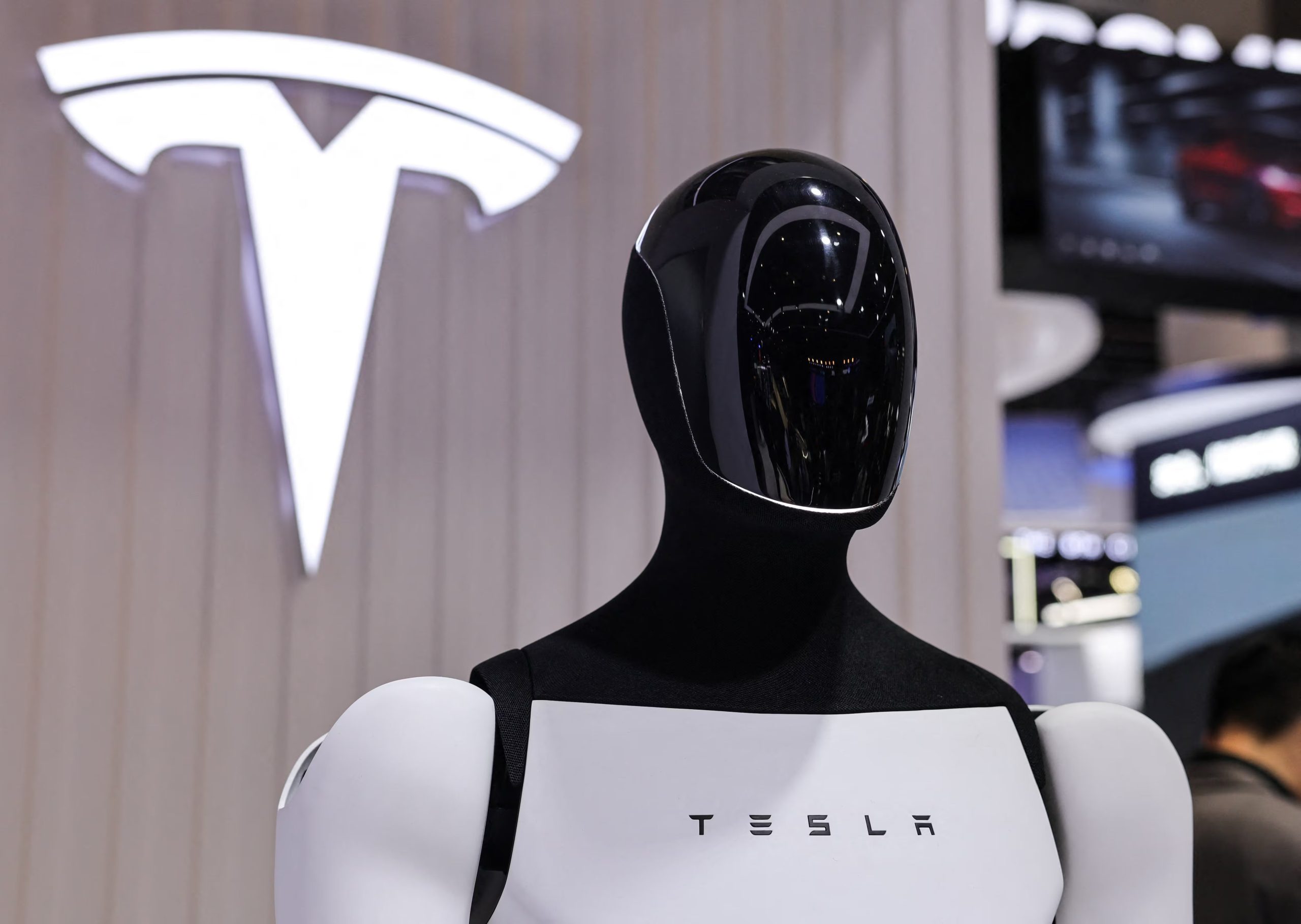 A Tesla Optimus robot is displayed next to a logo at the company’s booth at the 8th China International Import Expo (CIIE) in Shanghai, China, November 6, 2025.REUTERS/Maxim Shemetov