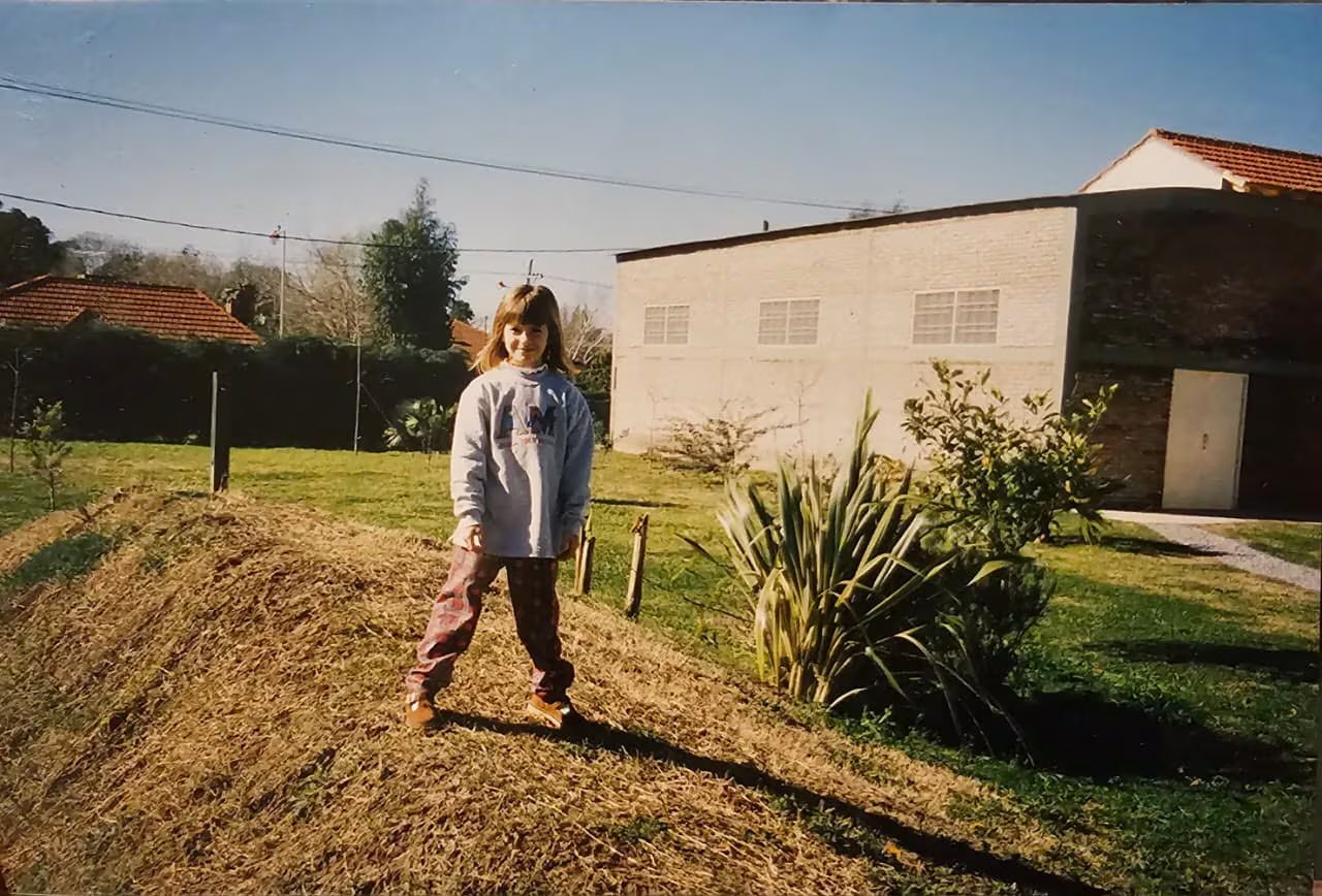 Foto de la infancia: Antonella posa en el jardín de su casa con el galpón ya terminado por detrás