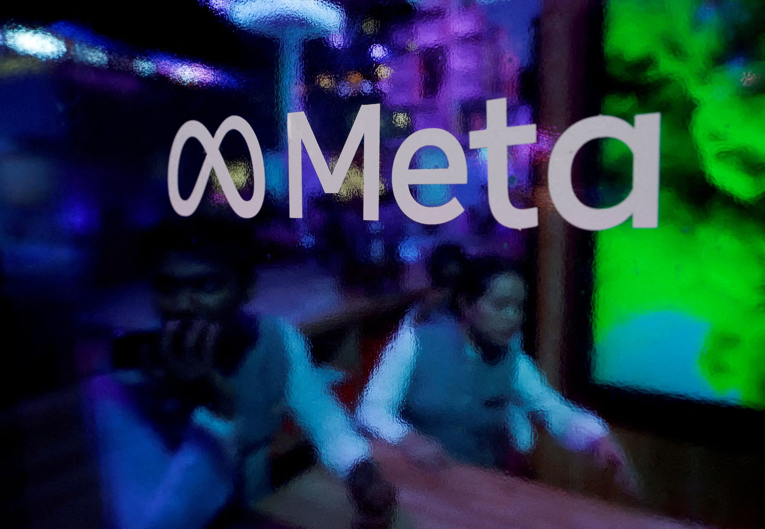 FILE PHOTO: People are seen behind a logo of Meta Platforms, during a conference in Mumbai, India, September 20, 2023. REUTERS/Francis Mascarenhas/File Photo