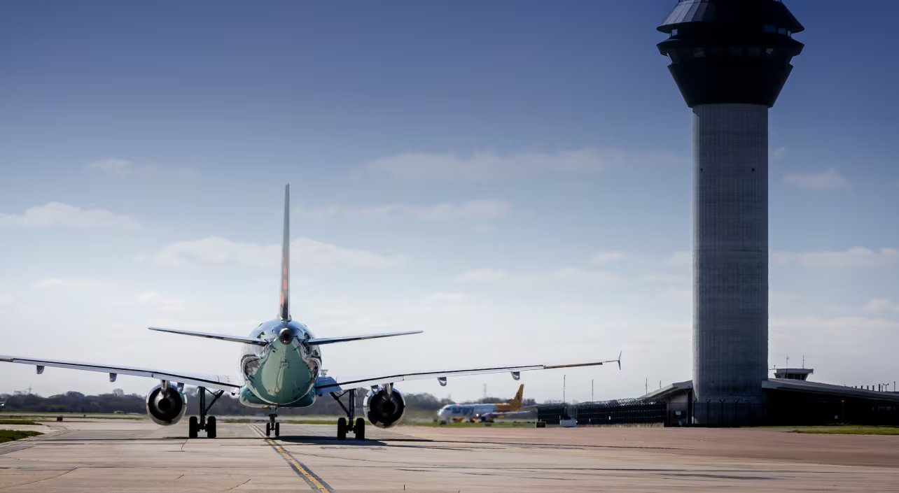 Un avión comercial maniobra en la pista junto a la torre de control en un aeropuerto. (Manchester Airports Group)