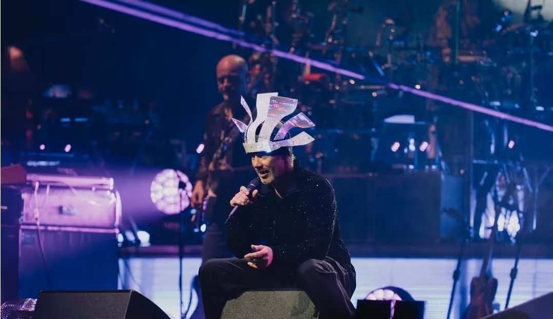 Al frente, Jay Kay volvió a ocupar el centro de la escena. Saltó, bailó, lanzó patadas al aire, recorrió el escenario de punta a punta y apareció con varios cambios de vestuario, entre sombreros excéntricos, gorros de plumas sintéticas y su habitual look deportivo.
