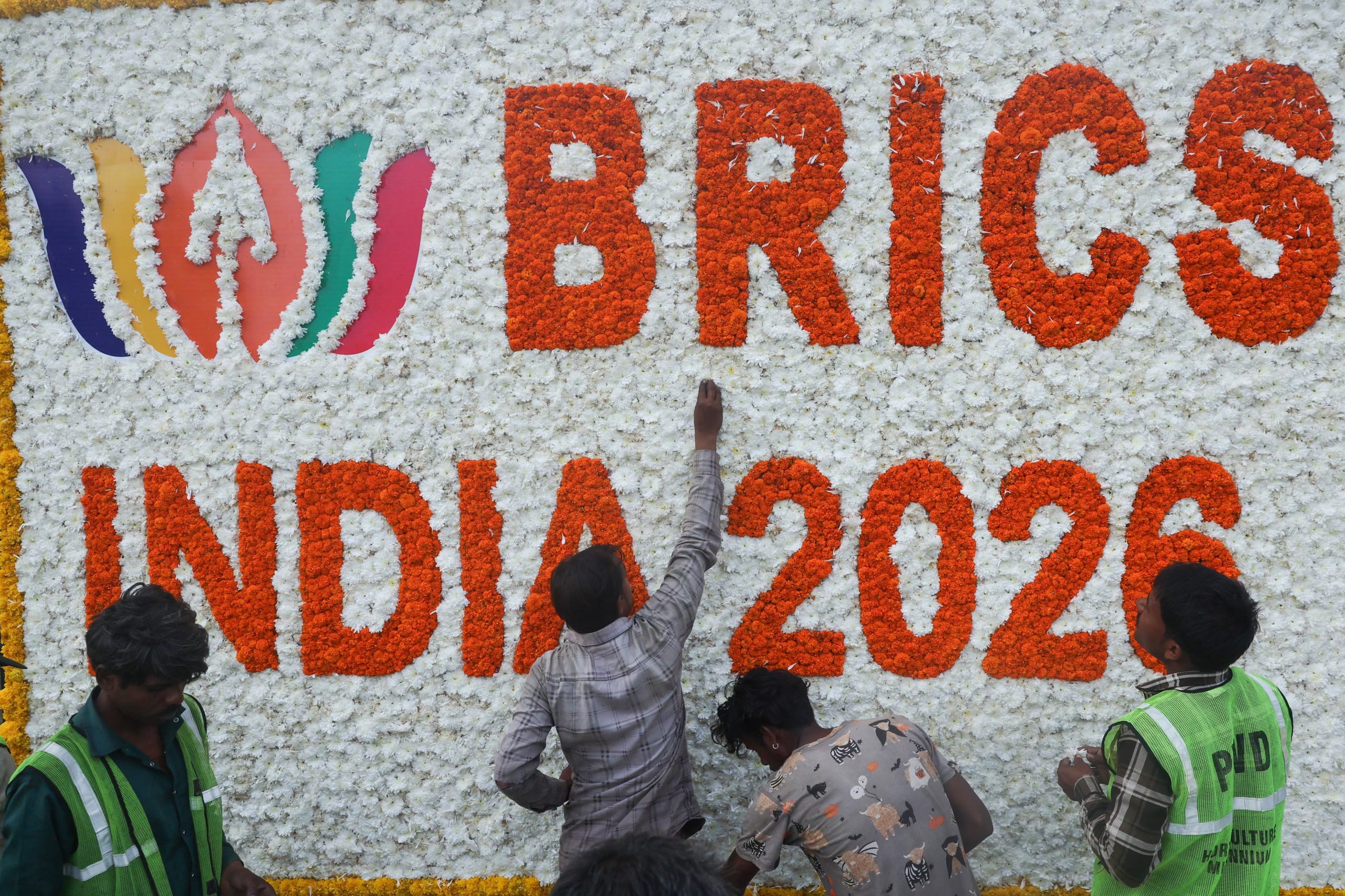 Unos trabajadores colocan flores en una decoración a la entrada del Bharat Mandapam, sede de la 18.ª Cumbre de los BRICS, en Nueva Delhi, India, el 12 de septiembre de 2026 (REUTERS/Francis Mascarenhas)