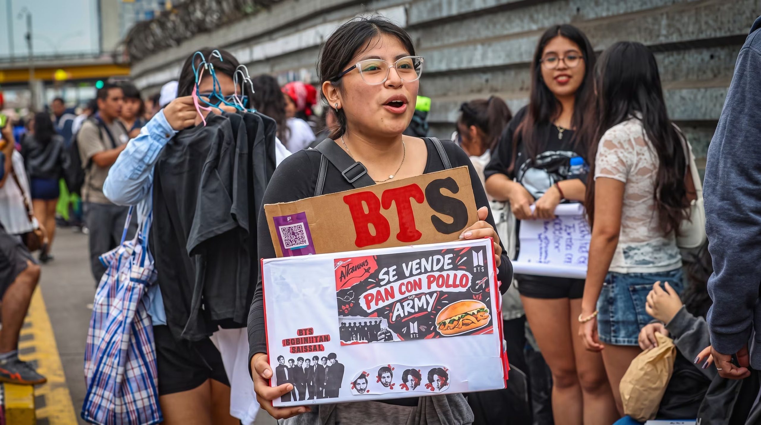 Una seguidora vende alimentos con un cartel del grupo surcoreano BTS durante una reunión de fanáticos en la vía pública. (Imagen Ilustrativa Infobae)