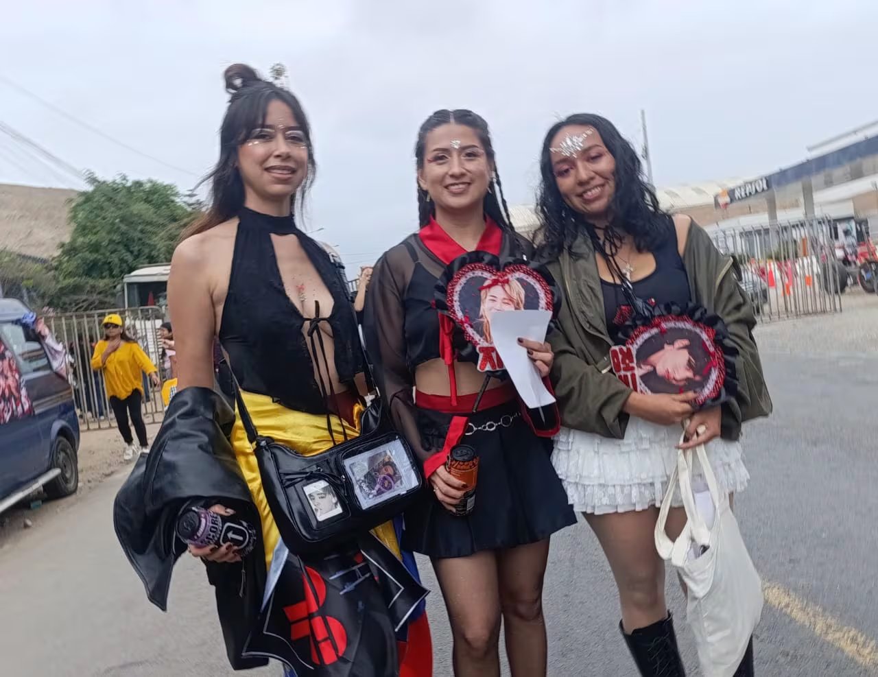 Tres seguidoras de la banda BTS posan con mercancía conmemorativa en las inmediaciones del Estadio San Marcos. (Infobae / Paula Díaz Elizalde)