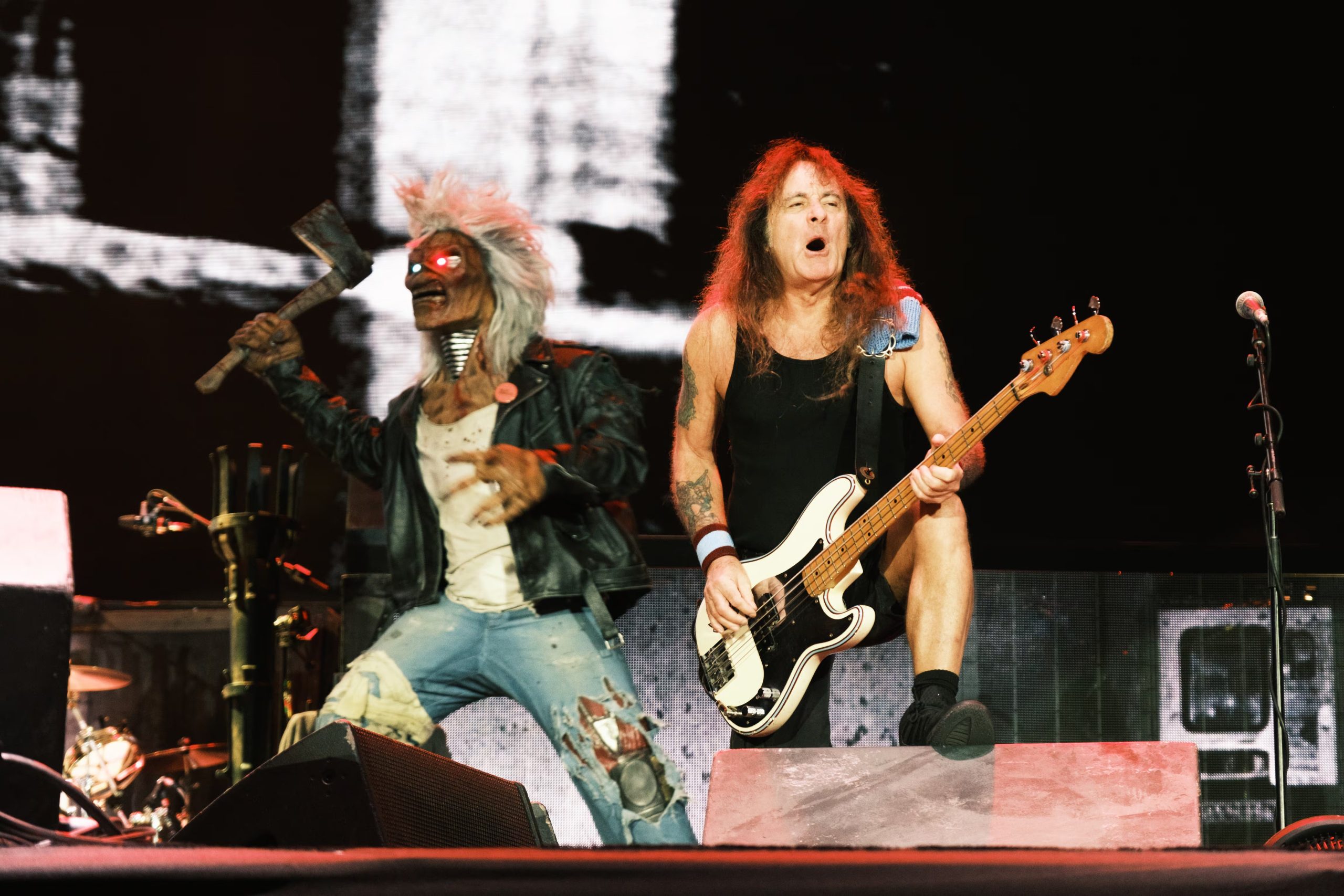 El bajista Steve Harris toca su instrumento en el escenario junto a la mascota caracterizada de la banda durante un concierto. (Liliana Estrada/Cortesía OCESA)