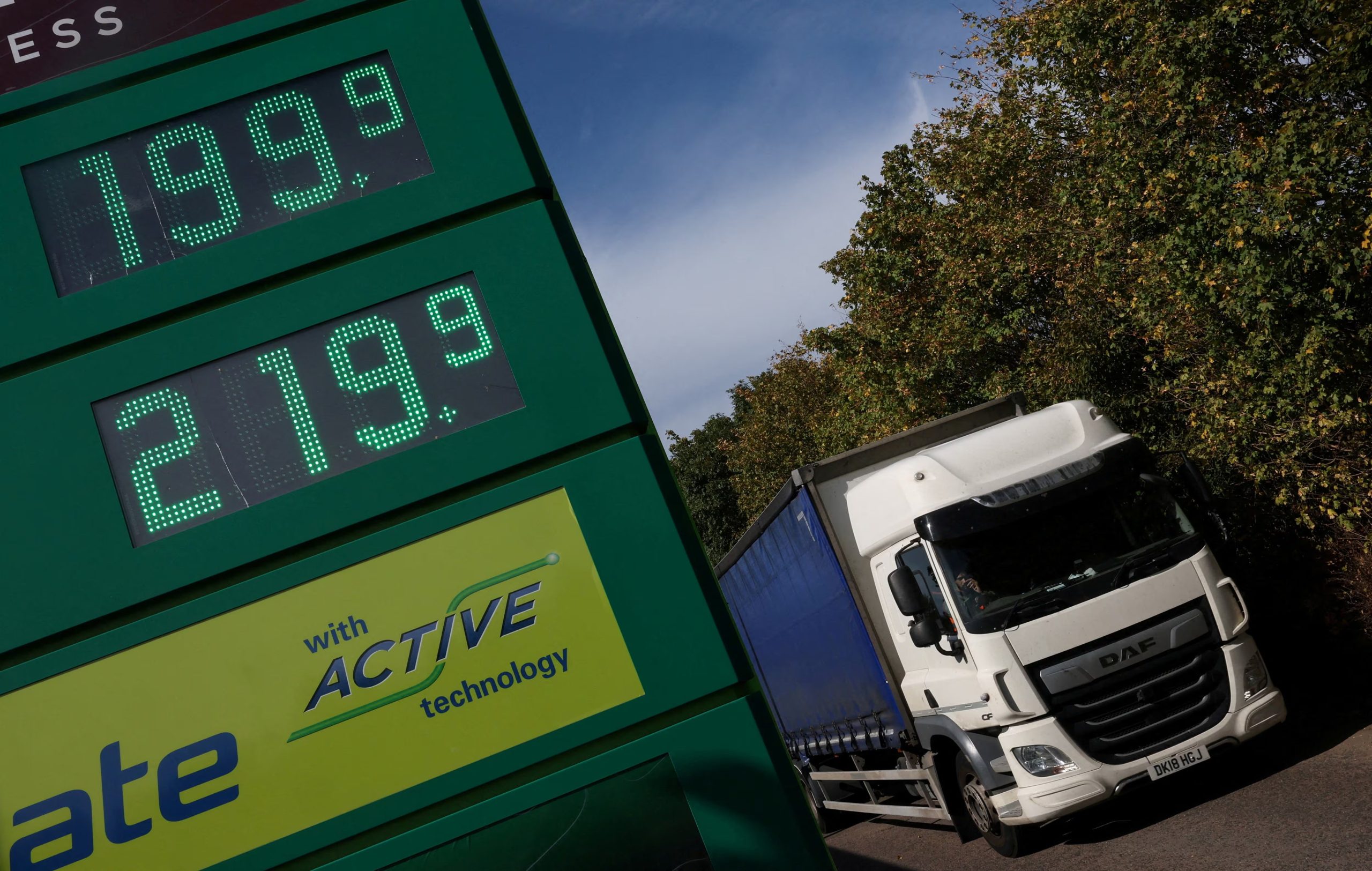 Un camión pasa junto a los precios en libras esterlinas por litro de gasolina sin plomo y diésel que se muestran en la entrada de una gasolinera de servicio de autopista en Reino Unido (REUTERS/Toby Melville)