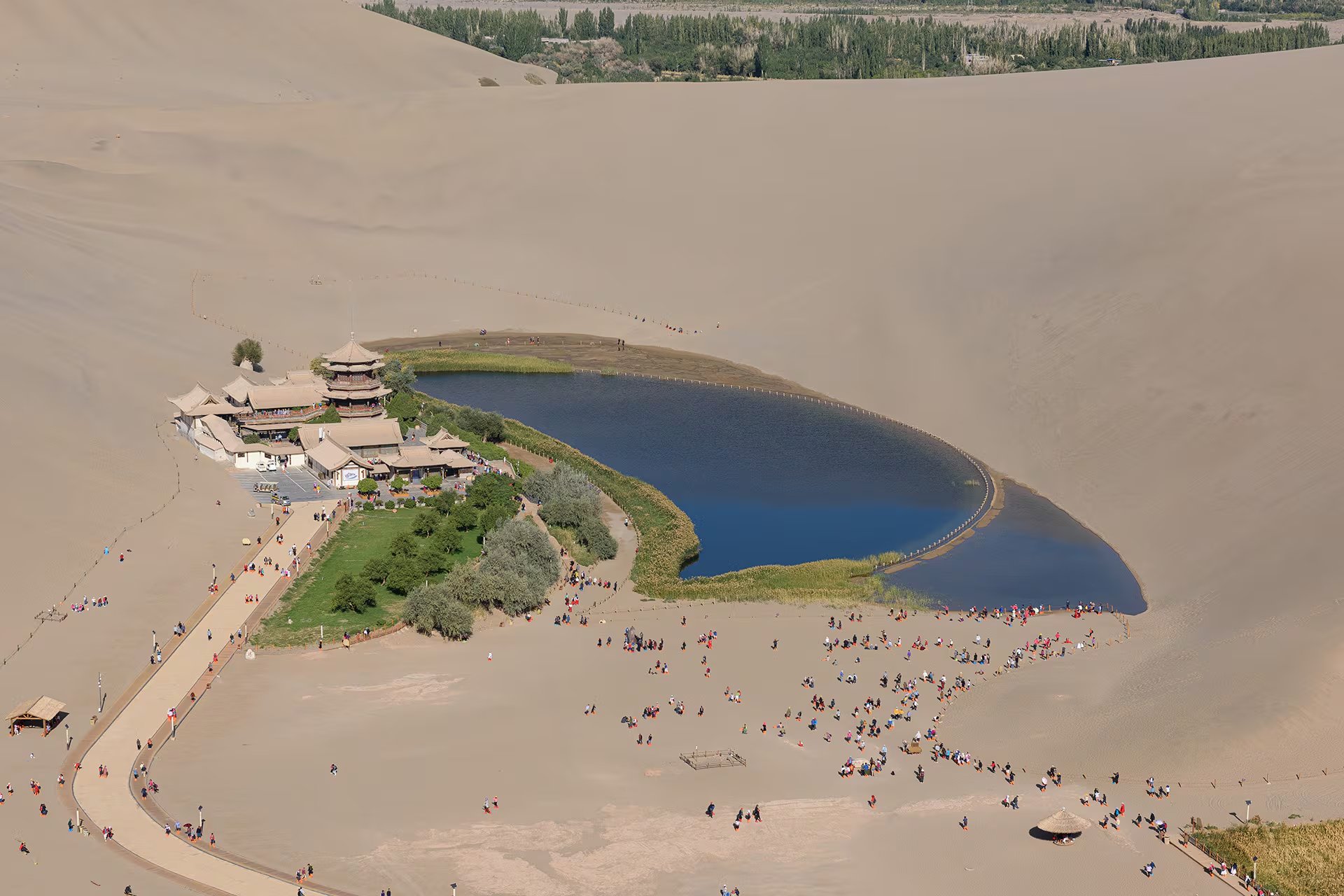 Un grupo de visitantes recorre el oasis del lago Yueyaquan, ubicado entre dunas de arena en la ciudad de Dunhuang, China. (Wikipedia)