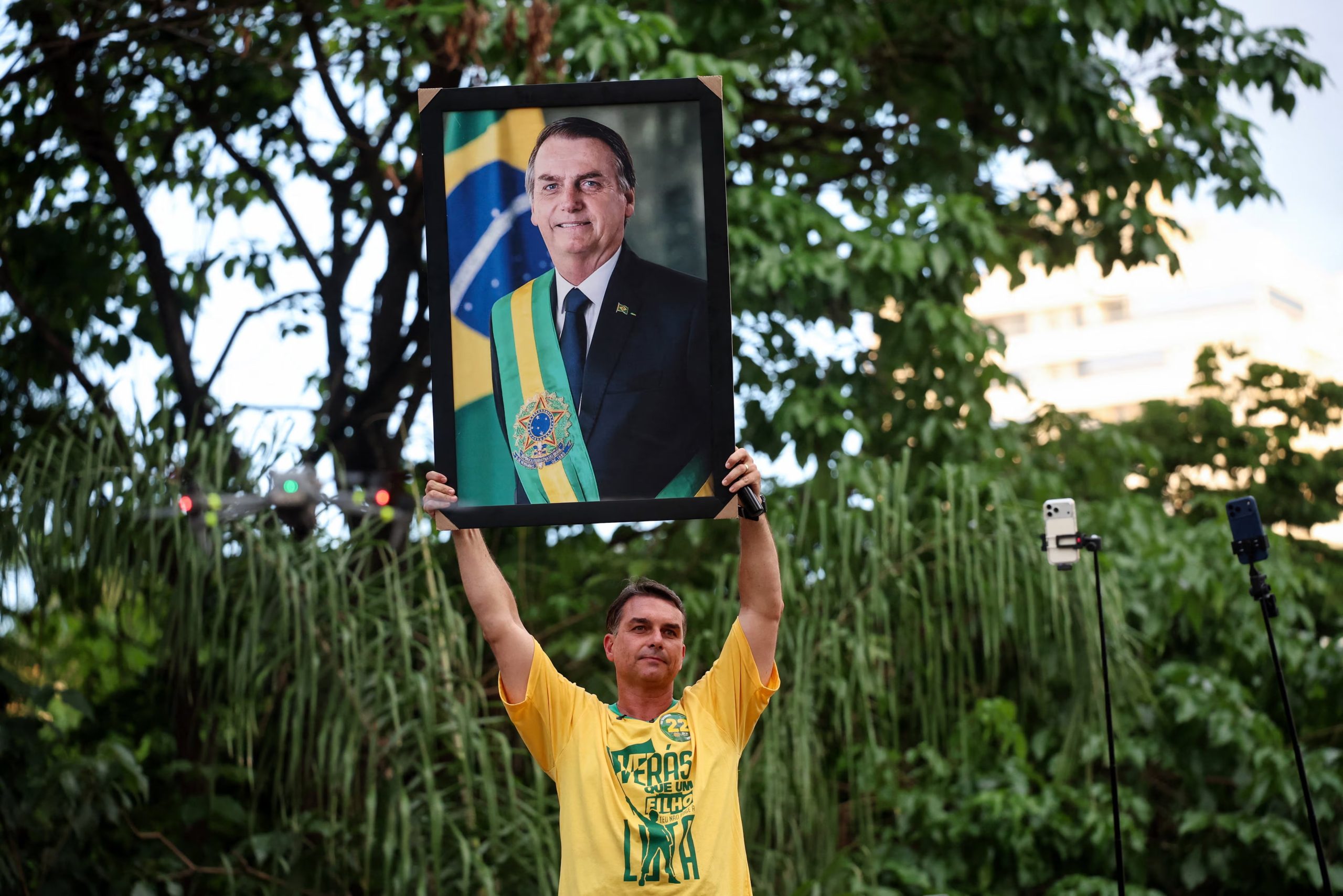 El candidato presidencial brasileño Flavio Bolsonaro, del Partido Liberal (PL), sostiene un retrato de su padre, el expresidente de Brasil Jair Bolsonaro, durante un mitin de campaña en Goiânia (REUTERS/Adriano Machado)